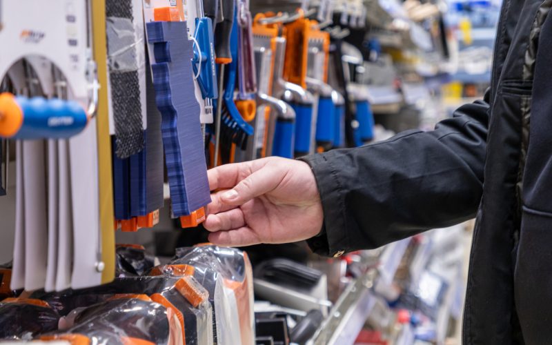 contour gauge tool for copying shapes, hand selecting a flexible measuring template in a hardware store aisle