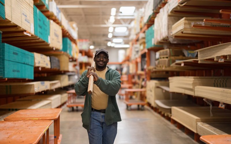 Happy man shopping for wood planks in hardware store